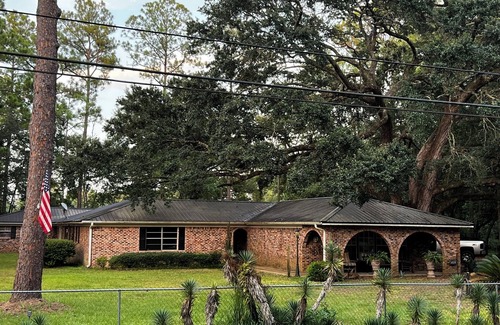 Moss Point House | Large fenced in home under a giant, moss covered, southern oak tree.