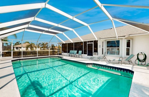 Pebble Beach House | Palm-lined waterfront retreat with enclosed pool, inviting patio, & central AC