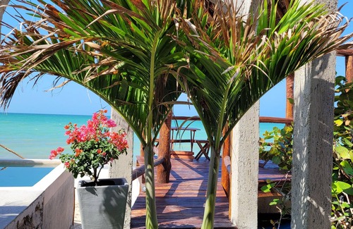 Chuburna Puerto Cottage | Pasilla suite. Ocean view glass doors to the turquoise water, 13foot Tv screen