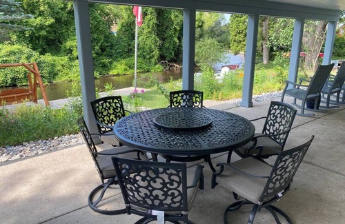 Grayling House | Riverfront Escape in Downtown Relax on the Covered Patio with the Family