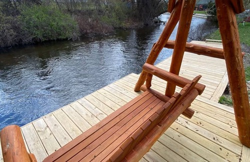Grayling House | Riverfront Escape in Downtown Relax on the Covered Patio with the Family