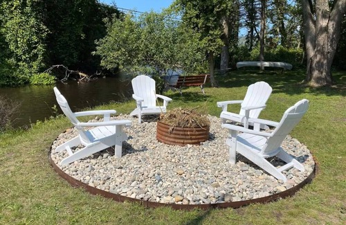 Grayling House | Riverfront Escape in Downtown Relax on the Covered Patio with the Family