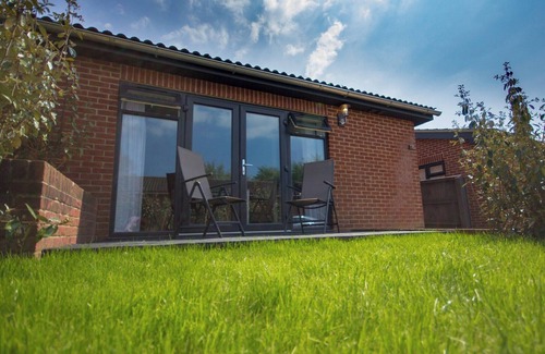 Rookley Cottage | Single-storey stylish open-plan living with French doors onto a deck and hedged lawn.