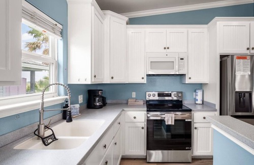 Leeward Sands House | "Step into Shark Attacks and embrace the coastal charm, setting the scene for a refreshing escape. With a spacious open floor plan, it's perfect for family gatherings and unforgettable memories."