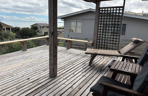 Ahipara House | Watch the waves from the large, sunny deck of this 1950's bach. Pet friendly.