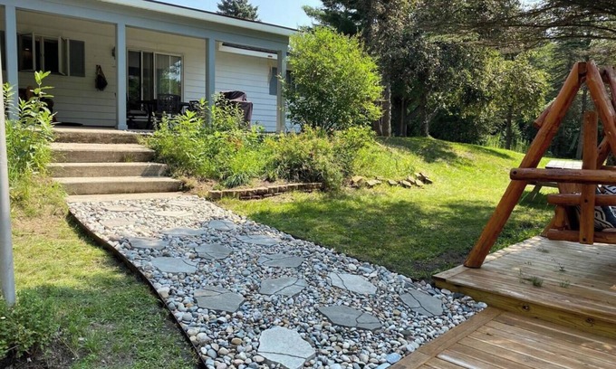 Grayling House | Riverfront Escape in Downtown Relax on the Covered Patio with the Family
