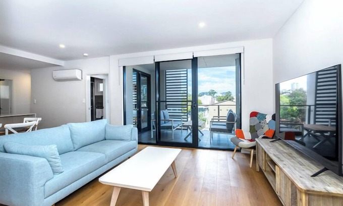 Leederville Apartment | Rooftop Sky Lounge has a daybed, tables and stools, a lounge area with a big screen TV and a grassed